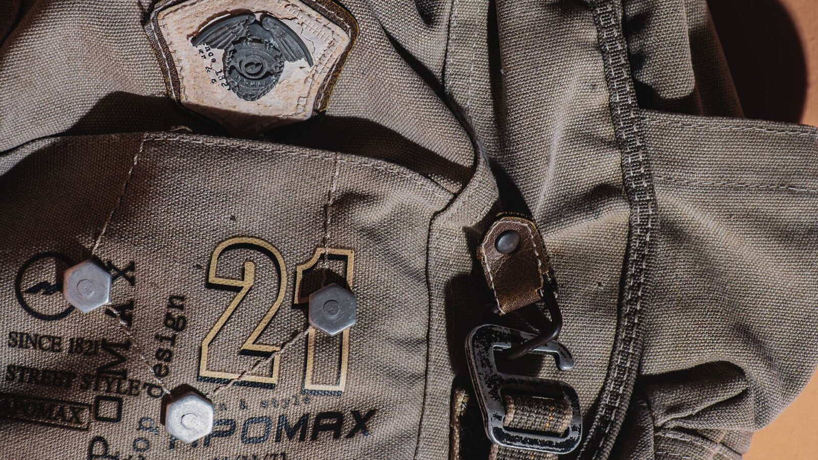 Detailed close-up of a rugged canvas backpack with military patch and metal hardware.