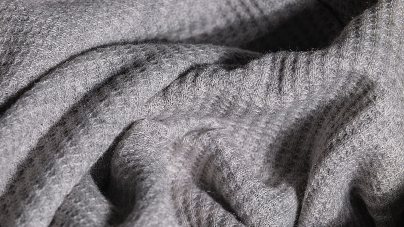 Close-up image of soft gray knitted fabric with intricate texture.