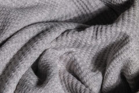 Close-up image of soft gray knitted fabric with intricate texture.