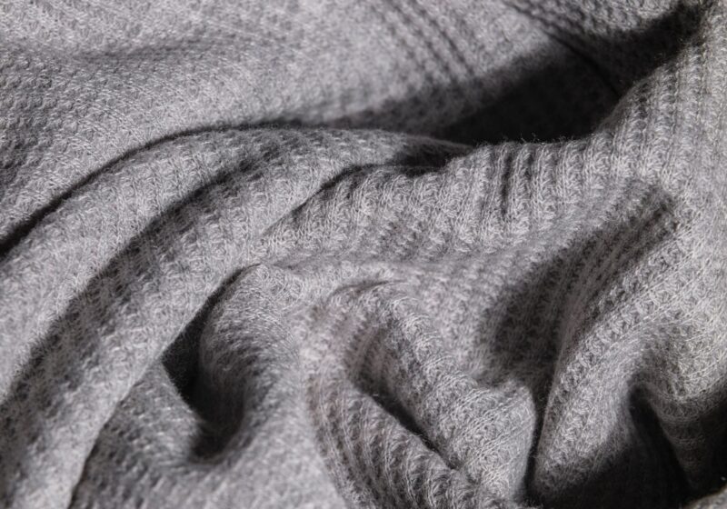 Close-up image of soft gray knitted fabric with intricate texture.