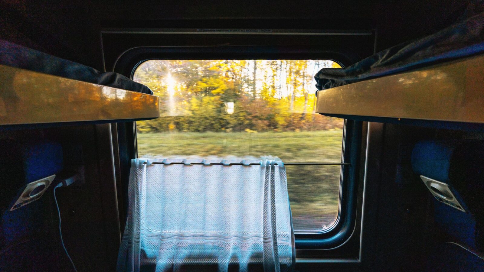 Interior view of a train cabin with autumn landscape outside, creating a serene travel atmosphere.