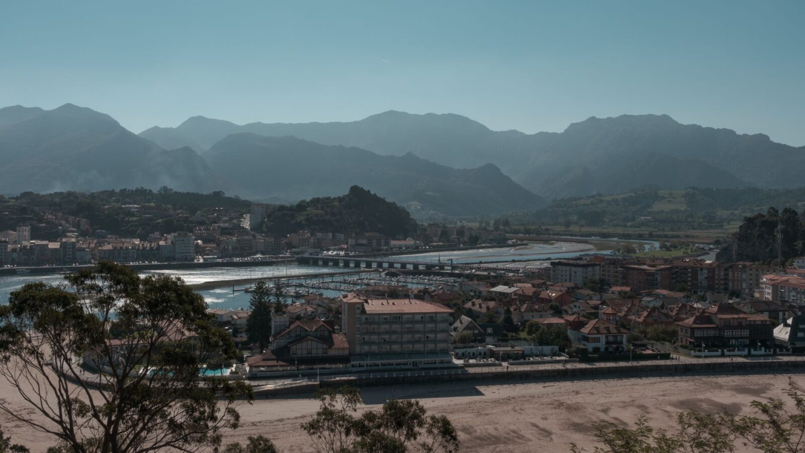 Scenic view of a coastal town in Asturias with mountains in the background, Spain.